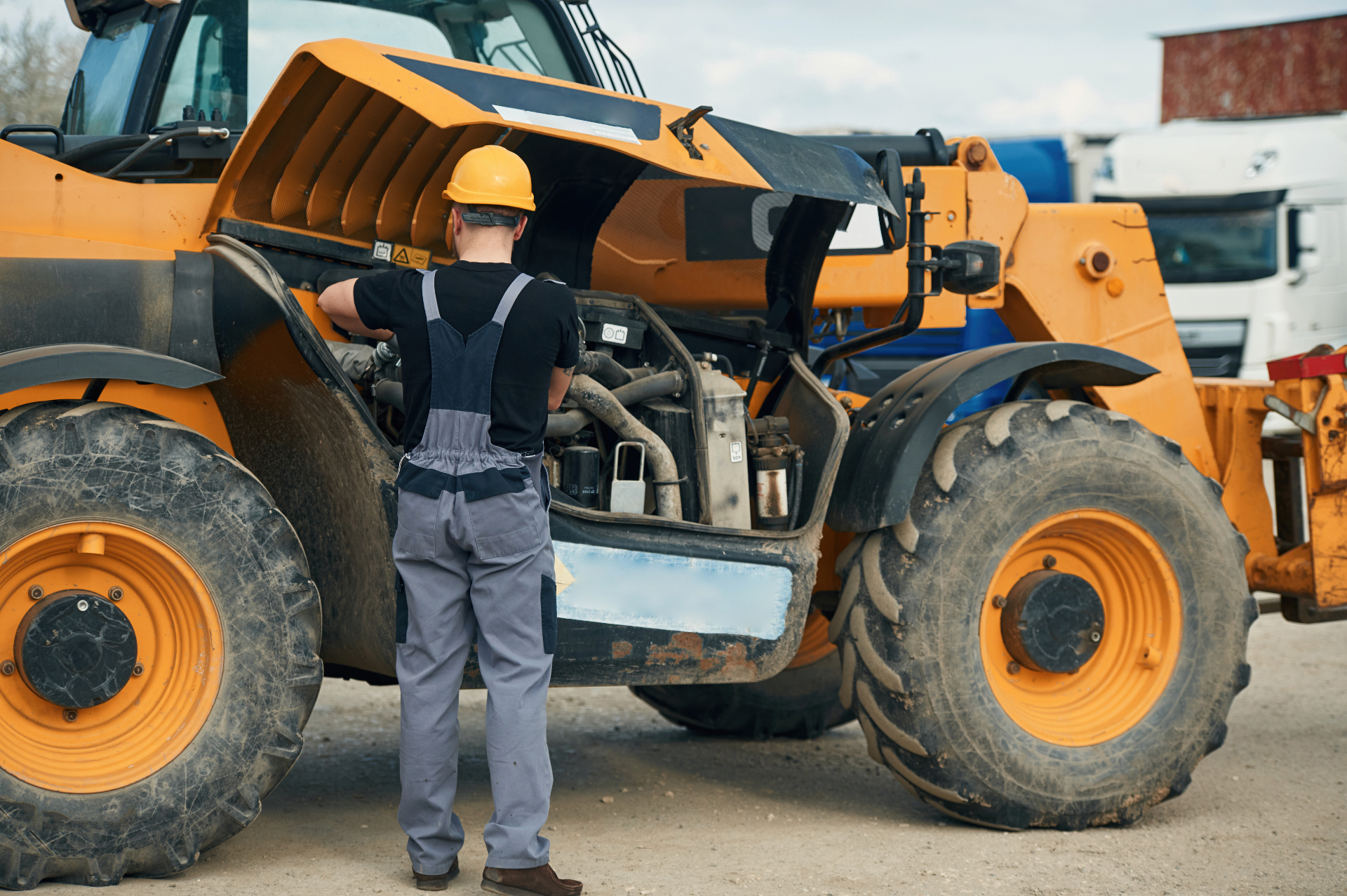 A mechanic working on the engine of a telehandler